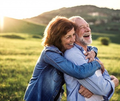 Husband and wife embracing in a lovely field as the sun rises