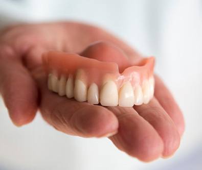 someone holding out a denture in their palm
