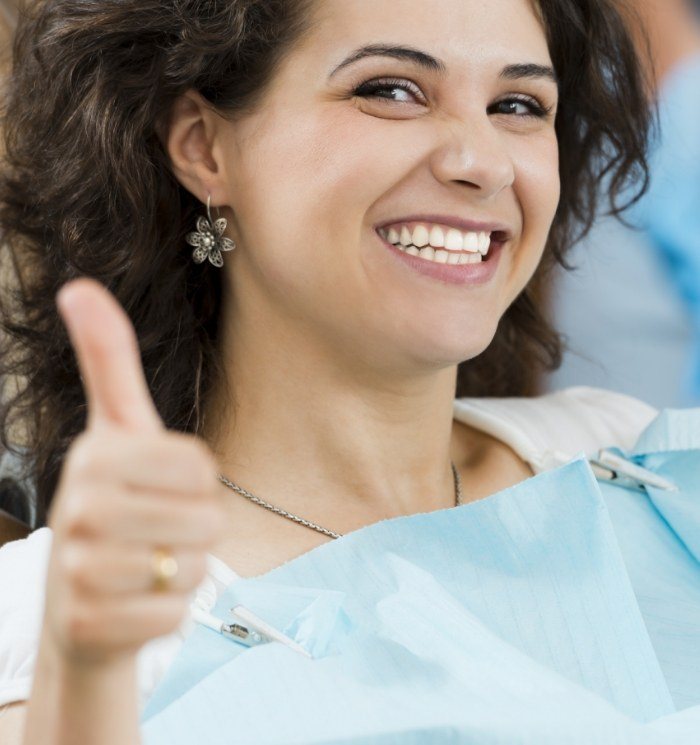 Woman giving thumbs up in dental chair