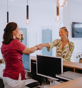 Patient and dental receptionist shaking hands in lobby