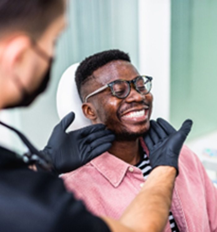Closeup of man in pink shirt smiling at dental checkup