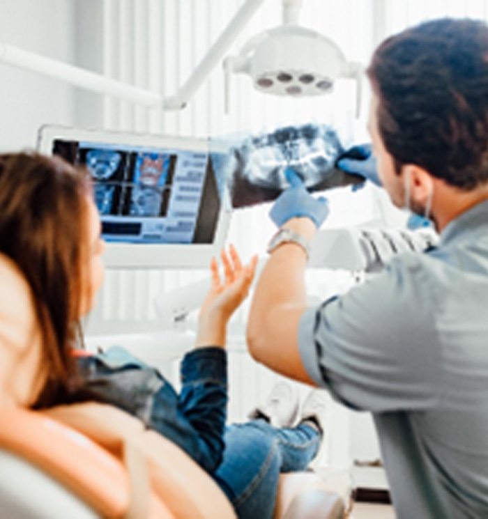 Dentist holding up X-ray and explaining findings to patient