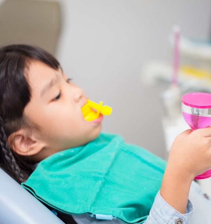 Young girl getting silver diamine fluoride in dental office