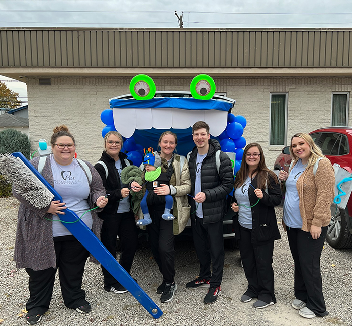 Dental team members holding giant toothbrush and toys for community event