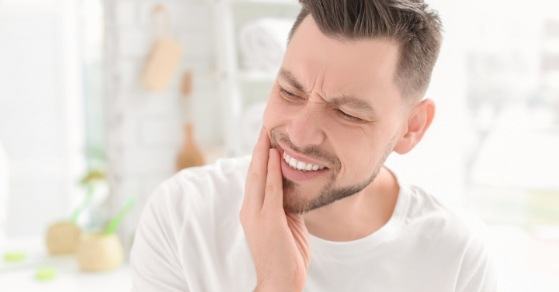 Man holding the side of his jaw in pain