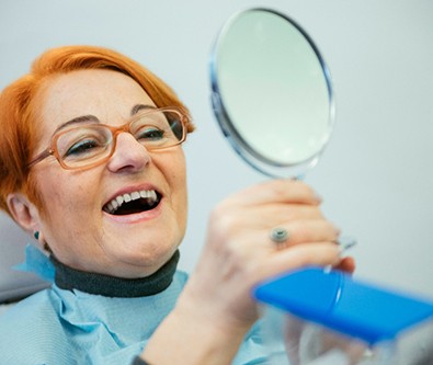 a patient examining her smile in a mirror