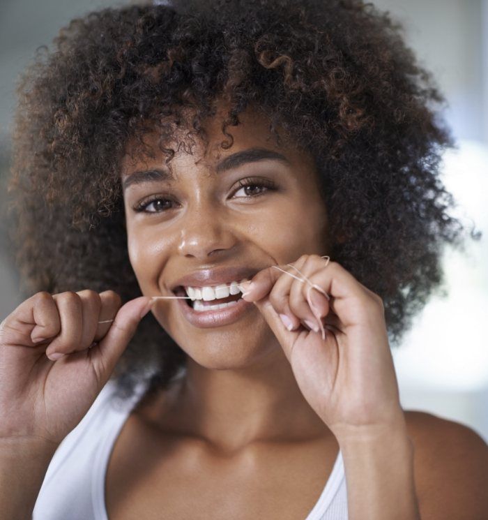 Woman smiling while flossing her teeth