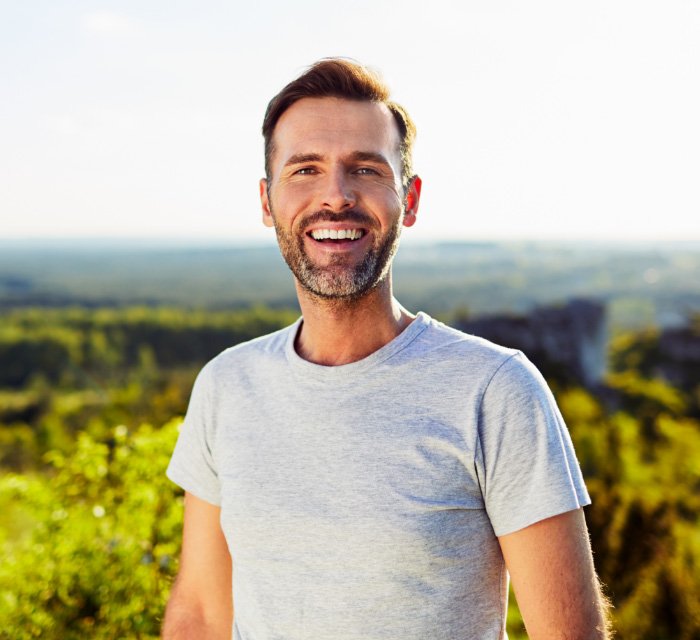 Smiling man in gray T shirt outdoors