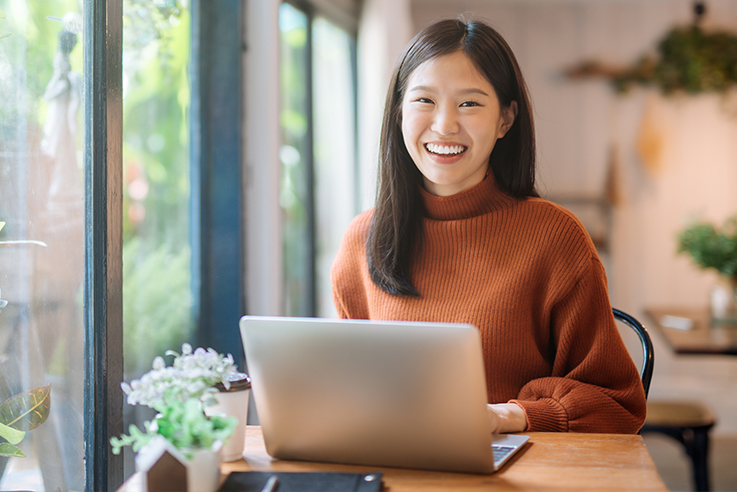 Smiling woman sitting at table with laptop