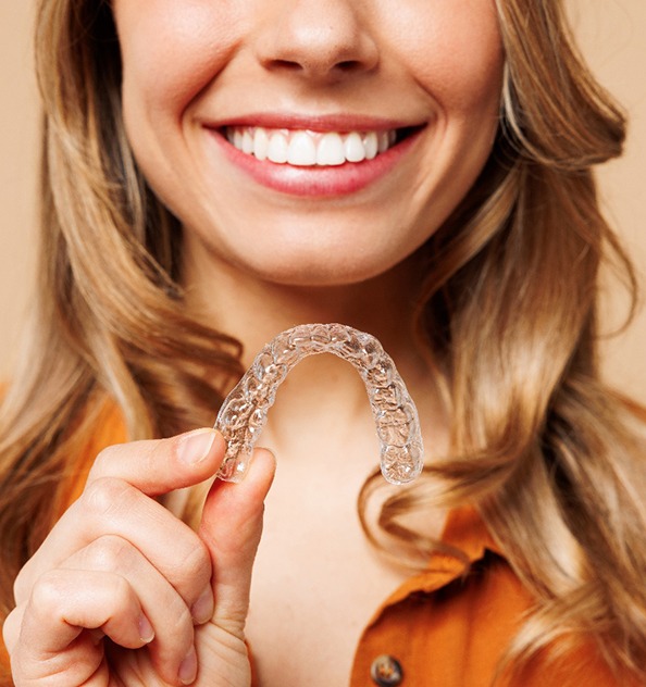 Young woman holding a SureSmile aligner in Waverly