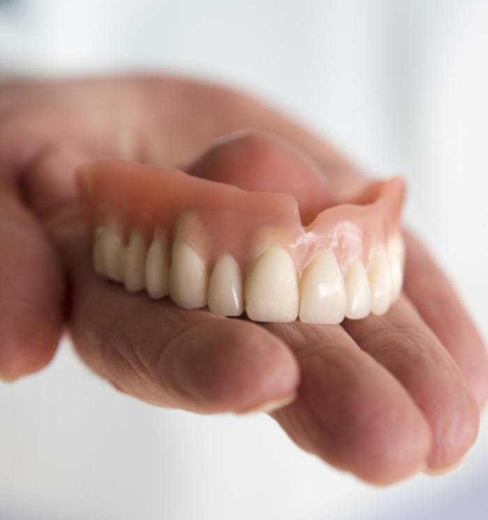 Hand holding a full upper denture