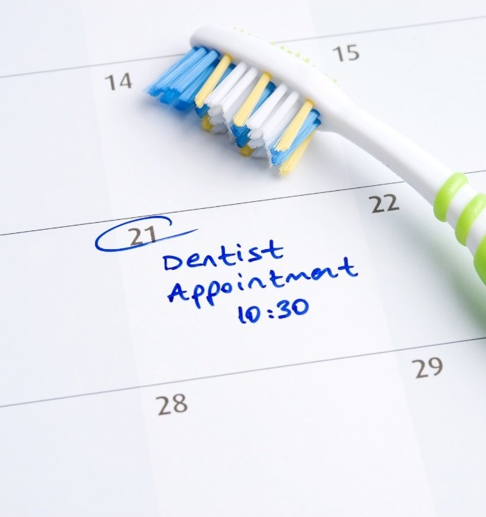Toothpaste next to calendar with dentist appointment written on one day