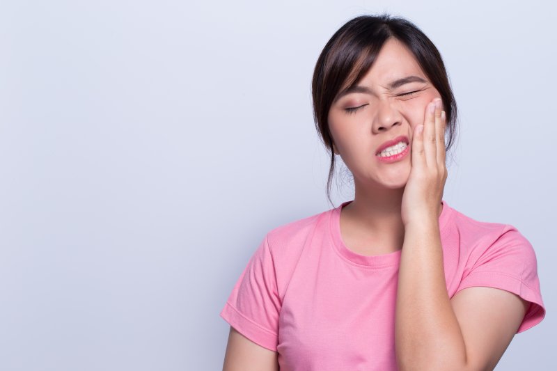 person with toothache holding their cheek