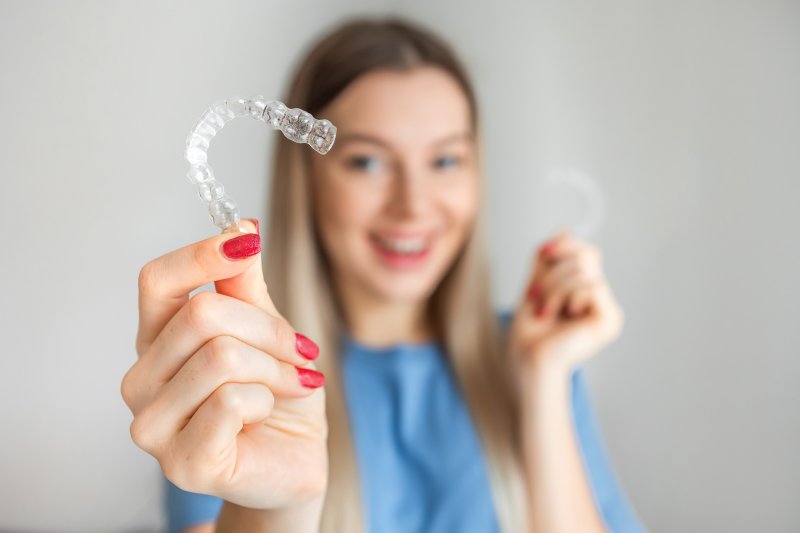 young girl holding clear aligners