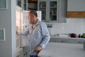 Senior man getting food out of a refrigerator