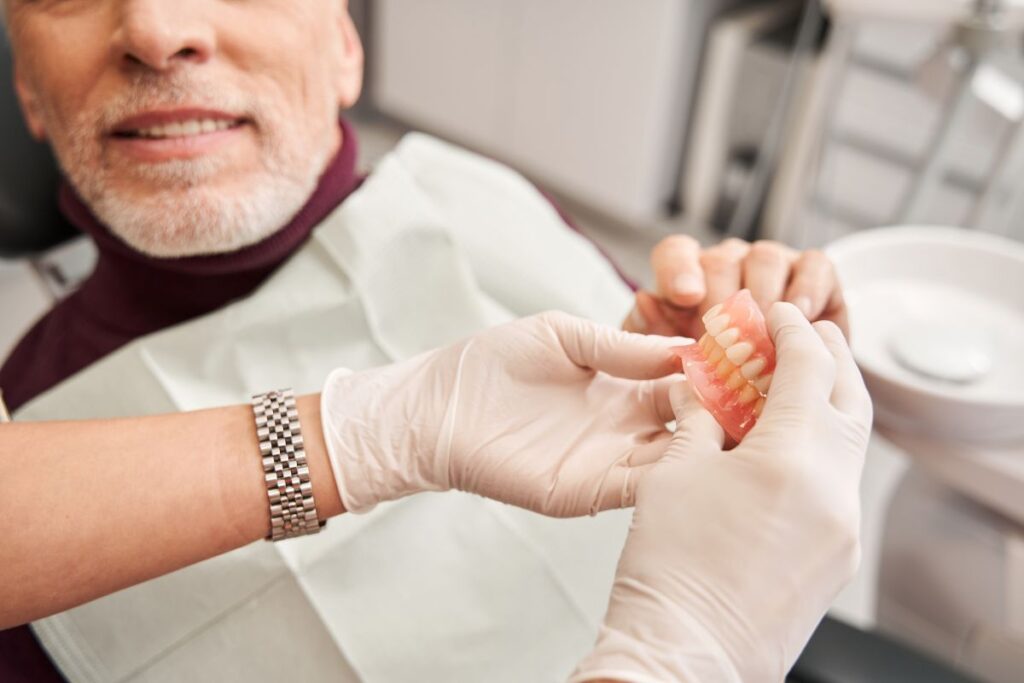 A man looking at a pair of dentures with his dentist